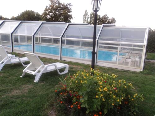 2 chaises et un pôle lumineux à côté de la piscine dans l'établissement GITE MONTPLAISIR, à Trancis