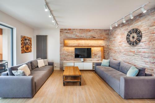a living room with two couches and a brick wall at Apartamenty Sun & Snow Stara Stocznia in Gdańsk