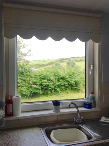 a window over a sink in a kitchen with a sink at Pant Glas in Cardigan