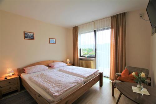 a bedroom with a bed and a window and a chair at Landgasthaus Rothbrust in Burgbrohl