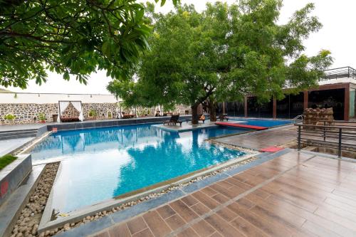 a swimming pool with blue water and trees at Fort JadhavGADH -A GADH Heritage Hotel in Pune