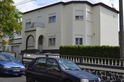 two cars parked in front of a white building at Casa Brito Aguiar in Angra do Heroísmo