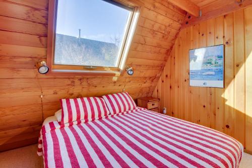 een bed in een houten kamer met een raam bij Seas the Day in Gearhart