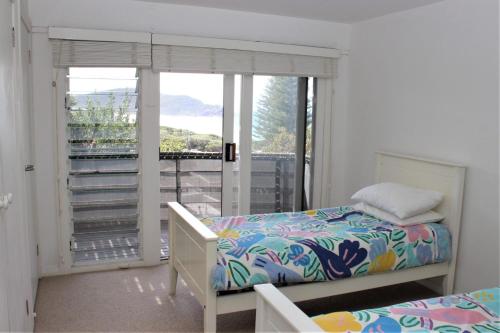 a bedroom with a bed and a window with a balcony at AQUA VIEW in Boomerang Beach