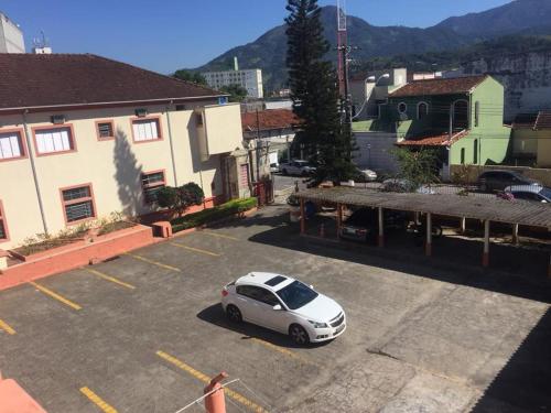 un coche blanco aparcado en un estacionamiento en Hotel Guanabara, en Caraguatatuba