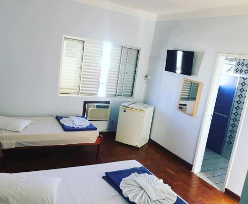 mały pokój z 2 łóżkami i lodówką w obiekcie Hotel Guanabara w mieście Caraguatatuba
