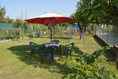 a table and chairs with an umbrella and a playground at Villa Luisa B&B in Candelo