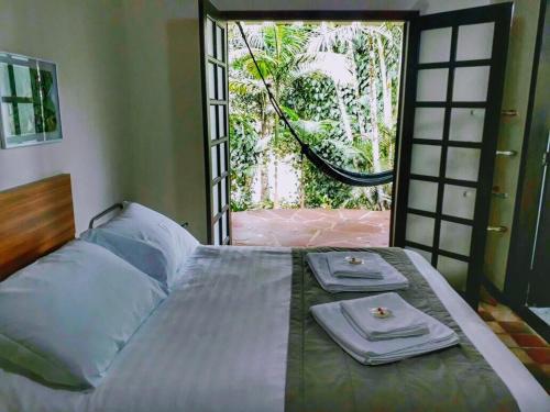 a bedroom with a bed with two towels on it at Gamboa Eco Refugio Pousada in Iporanga