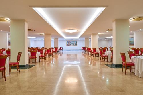una sala banchetti con tavoli e sedie rosse e cercatore di tavoli di Minerva Resort Hotel a Paestum