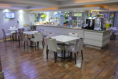 a restaurant with tables and chairs and a counter at AJ Hotel Chapecó - Fácil Acesso Pátio Shopping e Rótula da Bandeira in Chapecó