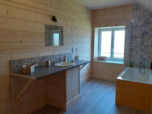 uma casa de banho em madeira com 2 lavatórios e uma banheira em LES TROIS CHARMES em Chaucenne