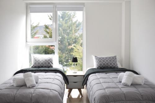 dwa łóżka w pokoju z oknem w obiekcie Bien al Sur w mieście Ushuaia