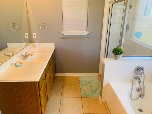 een badkamer met een wastafel, een bad en een douche bij Amazing House to Relax & Enjoy Austin - King Bed, Huge TV, Near Park & Shopping in Round Rock