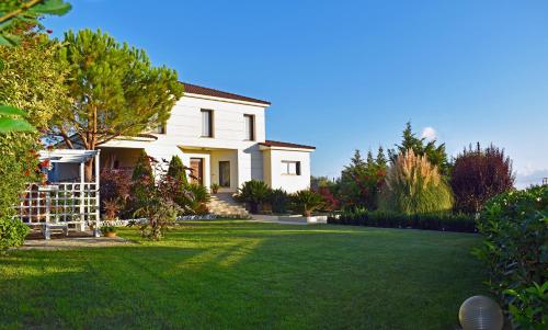 a white house with a green lawn at Villa Komfort in Zakynthos