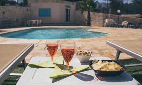 una mesa con dos copas de vino junto a una piscina en Villa Giuseppina en Monopoli