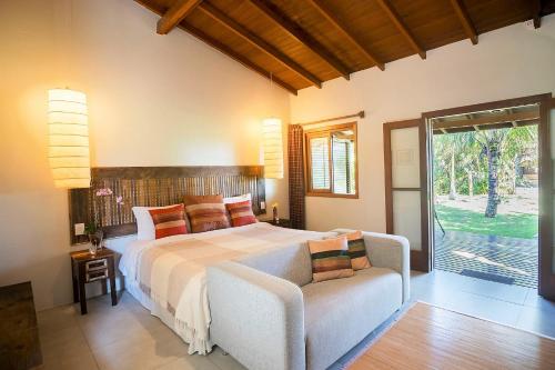 a bedroom with a bed and a couch and a window at Pousada Mevlana Garden in Barra de Ibiraquera