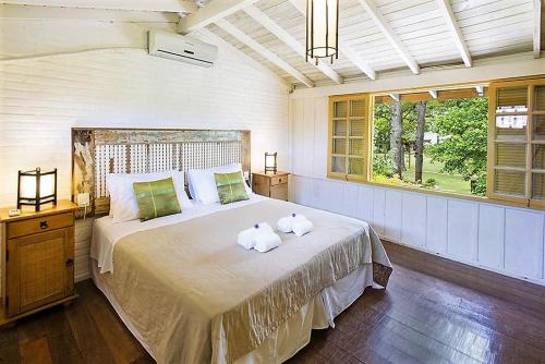 a bedroom with a large bed with two towels on it at Pousada Mevlana Garden in Barra de Ibiraquera