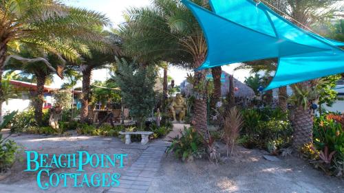 a blue umbrella in a garden with palm trees at BeachPoint Cottages in Siesta Key