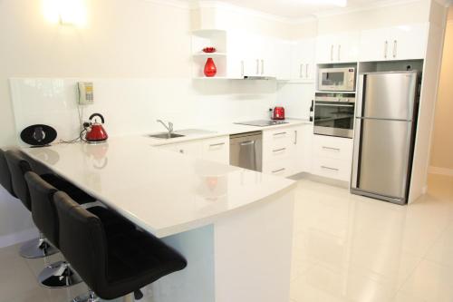 a kitchen with white cabinets and a stainless steel refrigerator at Outrigger Apartments Port Douglas in Port Douglas