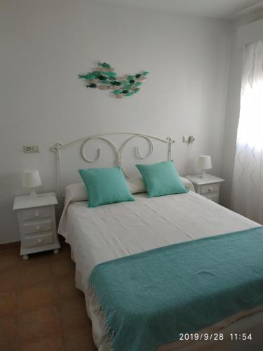 1 dormitorio con 1 cama grande con almohadas azules en Frente al mar, en Rota