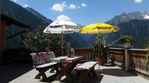 een patio met een tafel, 2 stoelen en een parasol bij Haus Bergblick in Prägraten