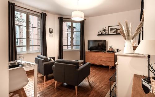 a living room with two chairs and a television at Au Coeur De La Ville in Honfleur