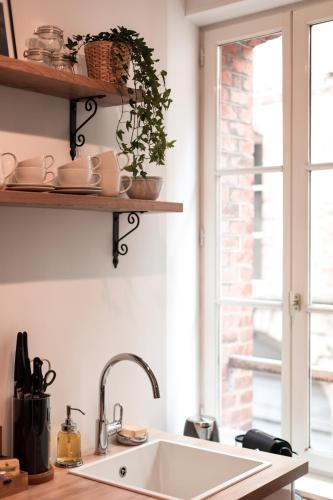 une cuisine avec un évier et une fenêtre dans l'établissement Au Coeur De La Ville, à Honfleur