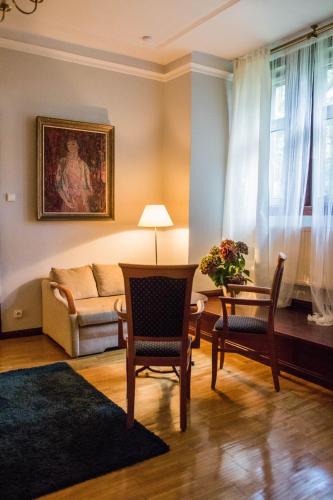 a living room with a couch and a table and chairs at Hotel Daria Dworek Myśliwski in Łódź