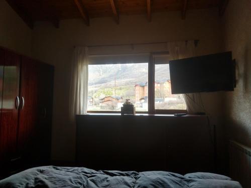 Dormitorio con ventana, cama y TV en Enjoy Catedral en San Carlos de Bariloche