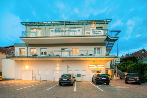 a building with a tower with cars parked in a parking lot at Schäfers Hotel, Self-Check-in, Cafe und Bäcker am Hotel in Vechta