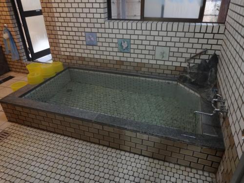 a bath tub in a bathroom with a tiled floor at Hanasaku Onsen Yoshiyaso in Katashina