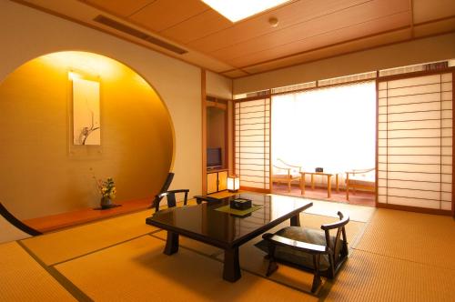 a living room with a table and chairs and a window at Arima Onsen Taketoritei Maruyama in Kobe