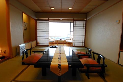 a room with a long table with chairs and a window at Arima Onsen Taketoritei Maruyama in Kobe