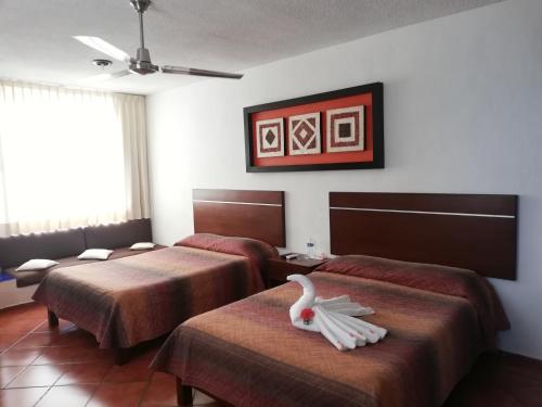 a hotel room with two beds with a swan on them at Hotel Los Girasoles in Cancún
