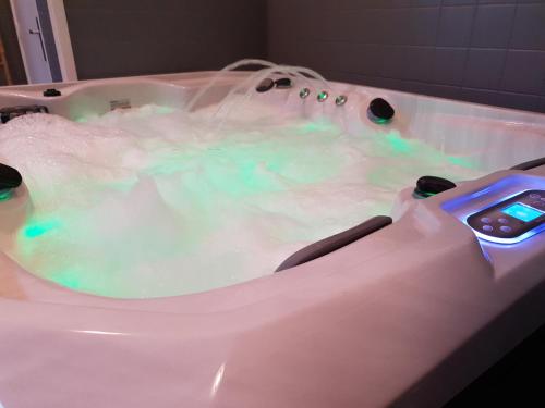 a bath tub filled with lots of white fluid at Cosy Er Lann Gîte Séquoïa in Val Couesnon