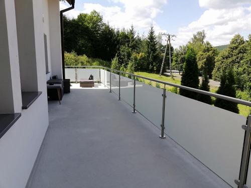 a balcony of a house with white walls and railing at Pokoje Na Szlaku in Lądek-Zdrój