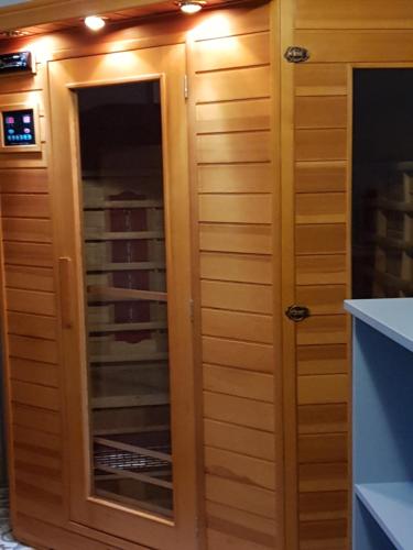 a wooden cabinet with a mirror in a kitchen at Cosy Er Lann Gîte Cèdre in Val Couesnon