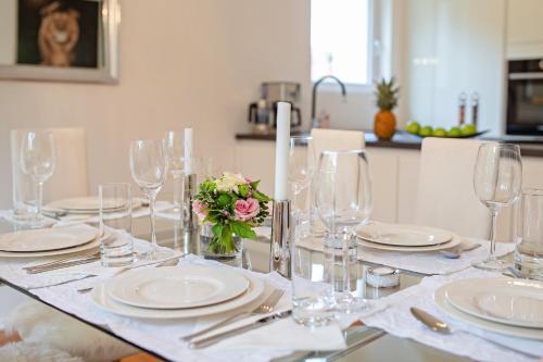 a table with glasses and plates and a flower on it at Family Apartment City Center Baden-Baden in Baden-Baden