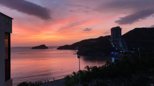 a sunset over the ocean with a building on a hill at Apartamento 10c Edf.Playa in Santa Marta