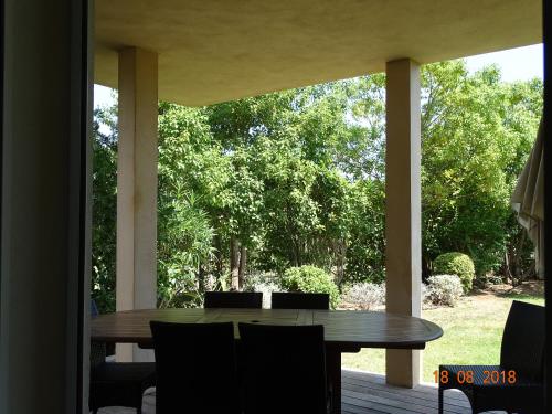 une table et des chaises en bois sur un porche dans l'établissement Résidence Coté Plage, à Sainte-Lucie de Porto-Vecchio