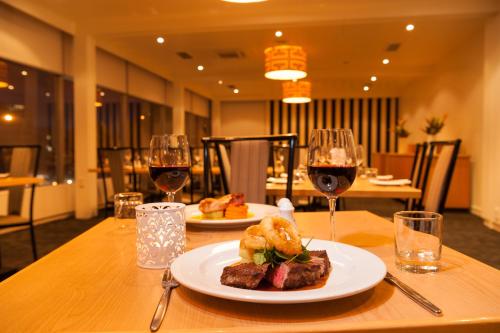 a table with a plate of food and two glasses of wine at Bay Plaza Hotel in Wellington