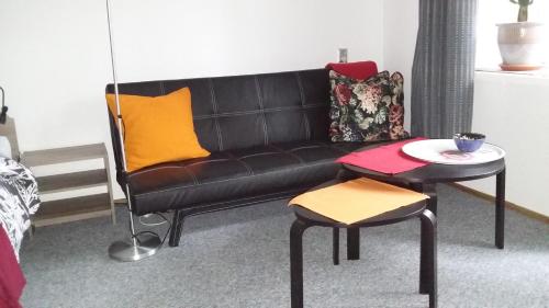 a black leather couch with a table and a stool at Animrumru in Warsaw