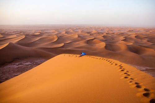 a person standing on top of a sand dune at Desert Atmosphere M'Hamid in Mhamid