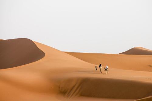 a group of people riding horses through the desert at Desert Atmosphere M'Hamid in Mhamid