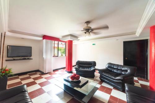sala de estar con muebles de cuero negro y TV de pantalla plana en Hotel Olimpico, en Barranquilla