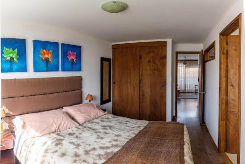 a bedroom with a bed and paintings on the wall at B&B HMüller in Pucón