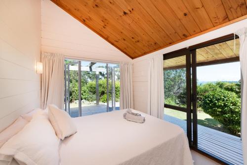 a bedroom with a bed and a large window at Waiheke Island Vineyard Holiday Houses in Surfdale