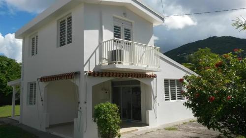 a white house with a balcony at Villa les Palmiers in Les Trois-Îlets