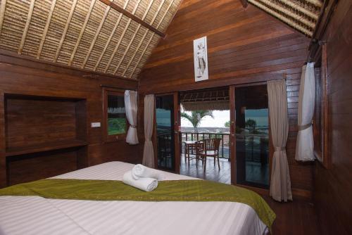 een slaapkamer met een bed en uitzicht op een balkon bij Twilight Ceningan in Nusa Lembongan