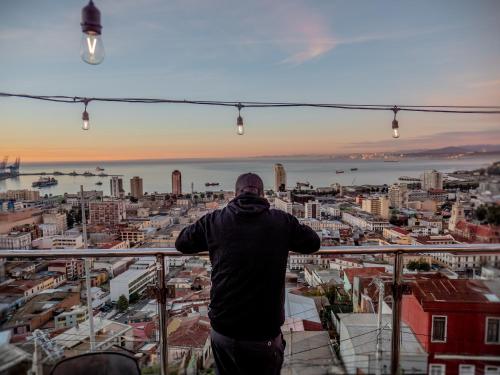 a man standing on the edge of a balcony overlooking a city at Hotel Winebox Valparaiso in Valparaíso